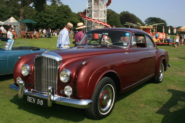 an old red car parked in front of other old cars