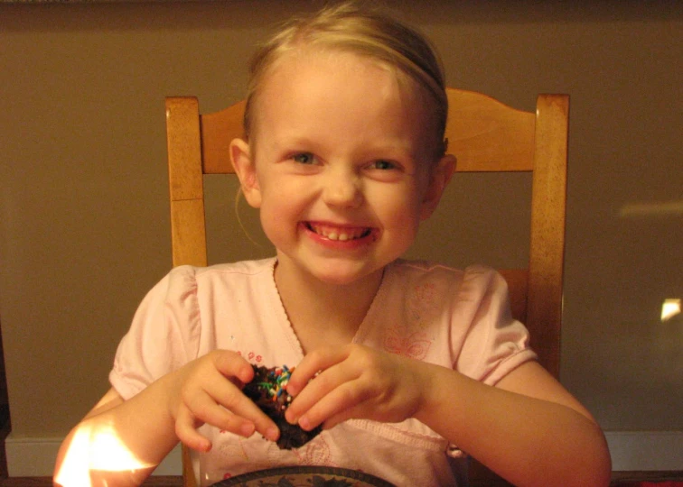 the child is sitting at the table with a lit candle