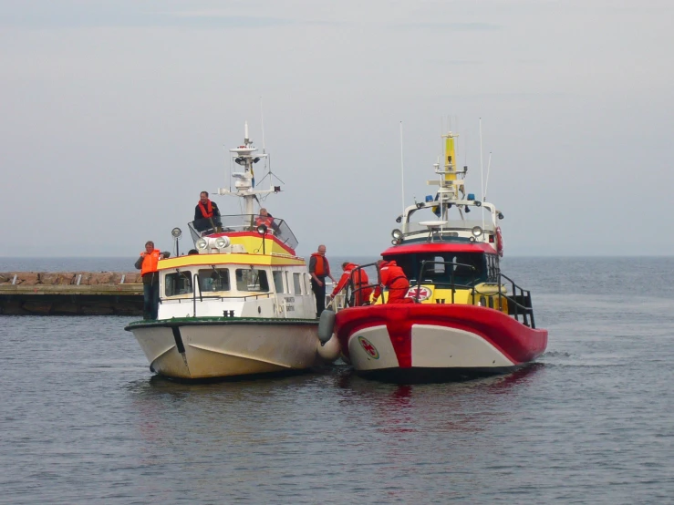 several boats are floating in the water with some people