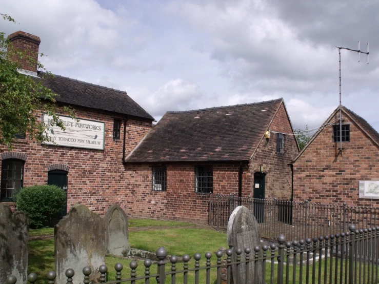 the stone walls and brick building is next to a graveyard