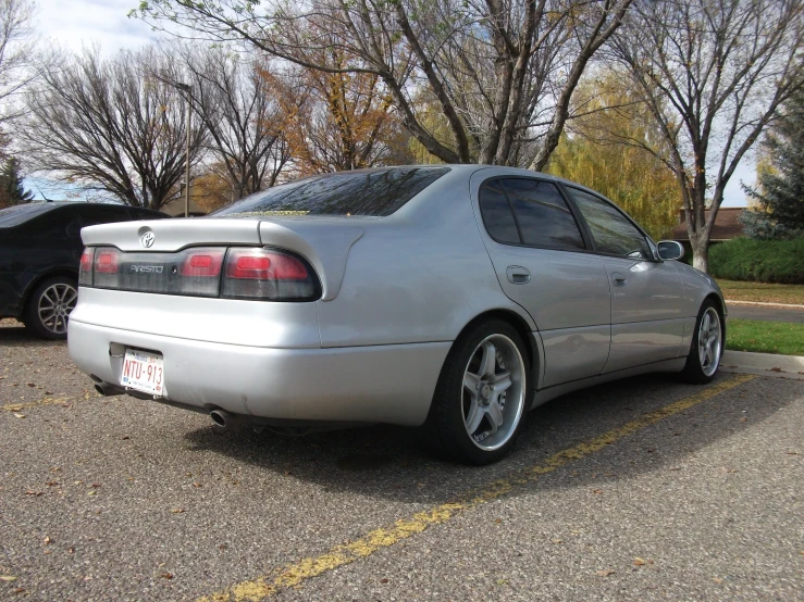 silver car is parked in a parking space next to trees