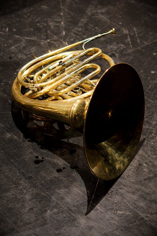 an antique french horn in gold against a black background