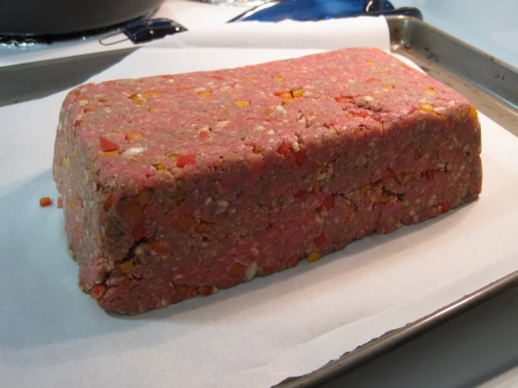 some raw meat on top of some paper next to a frying pan