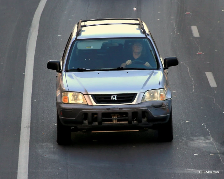 this is a grey suv driving down the road