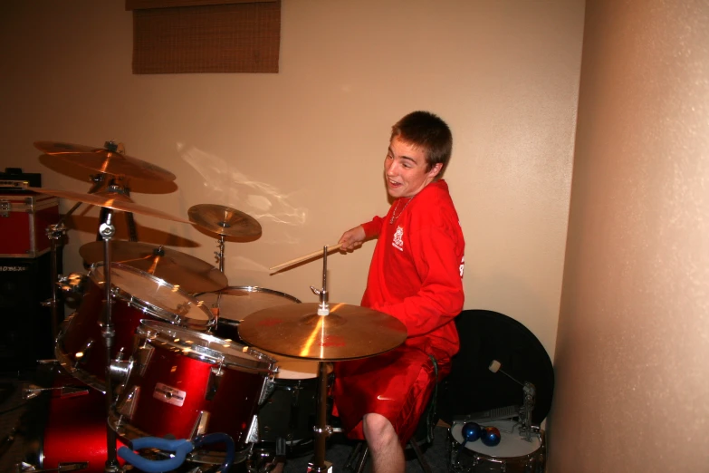 a boy in red plays the drums in a room