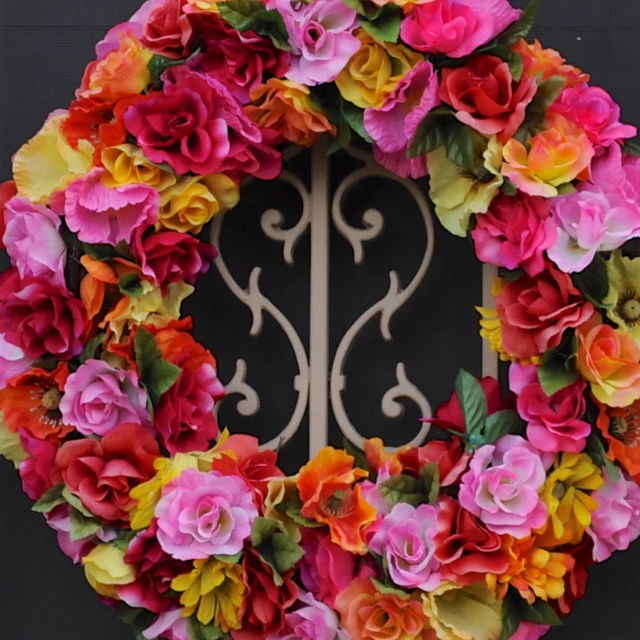 the wreath on the wall is covered with bright pink and yellow flowers