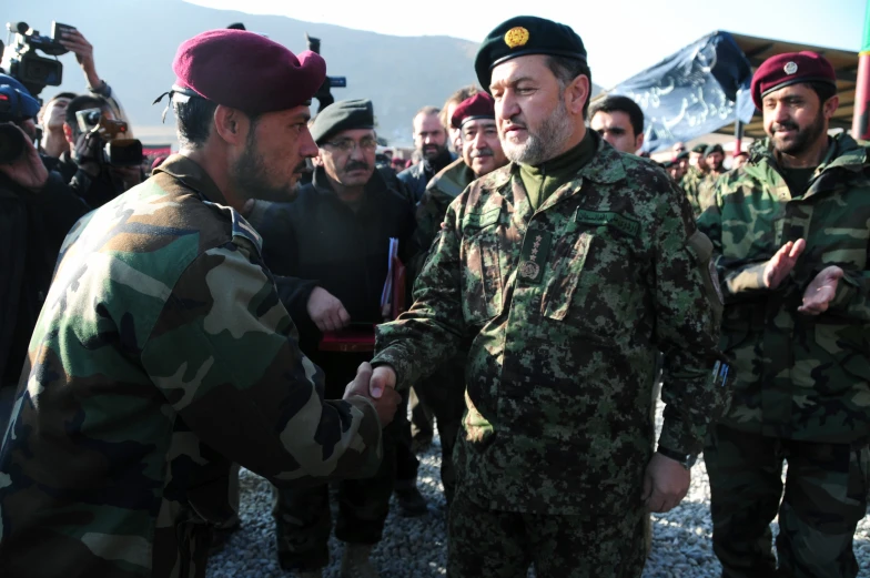 two soldiers shaking hands during an outdoor ceremony