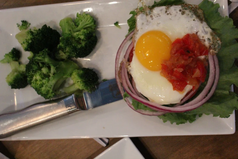 a plate has an egg, onions, and lettuce on it