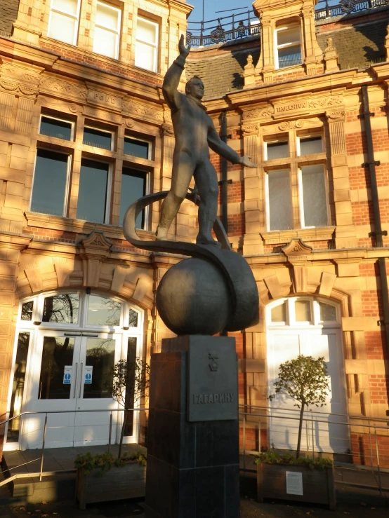 a statue on a rock with a building behind it