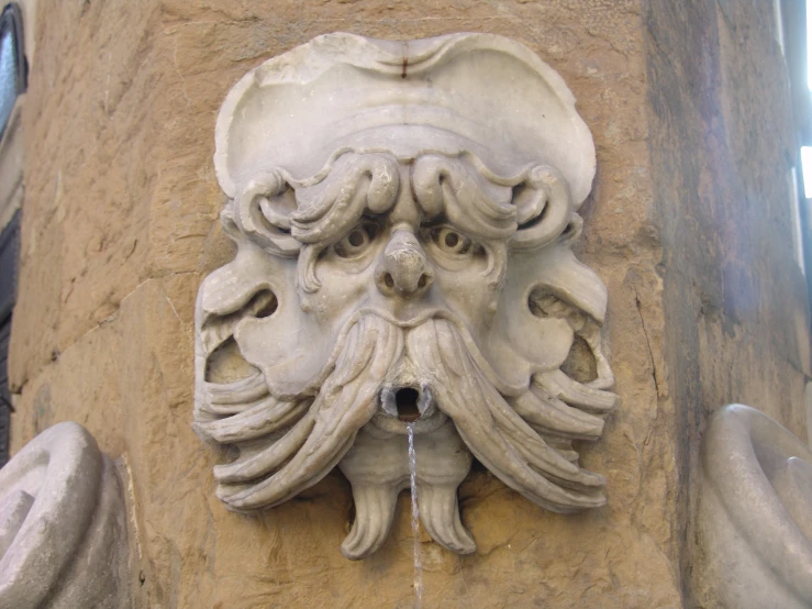 a water fountain has a large face carved into it