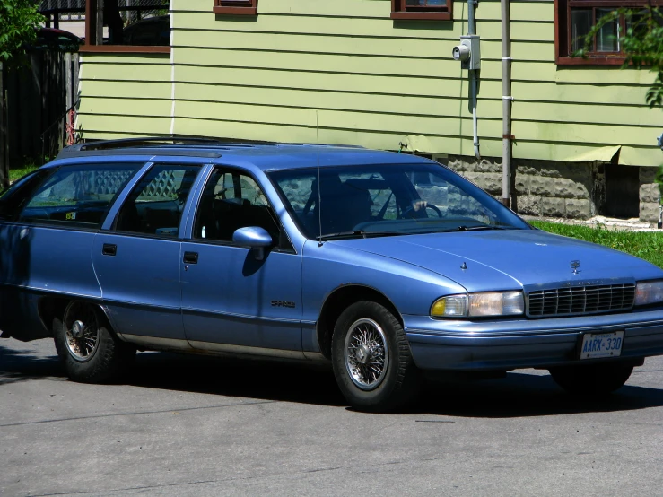 a blue station wagon parked in front of a green building