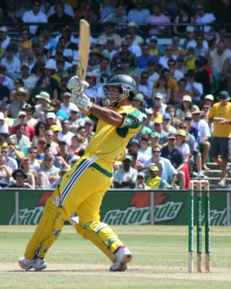 man in yellow pants swings his bat at the ball