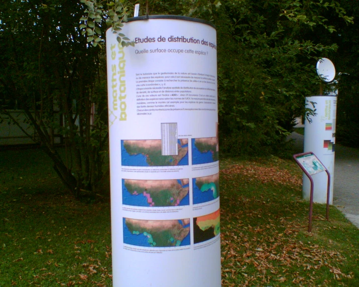 a large white sign next to trees with many signs