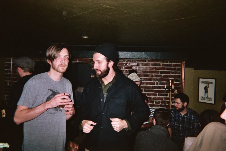 two men pose for the camera at a bar