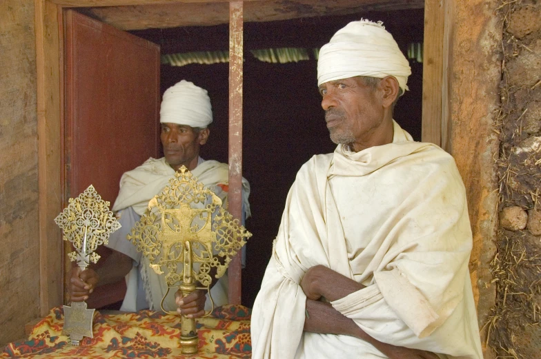 three men standing next to each other holding crosses