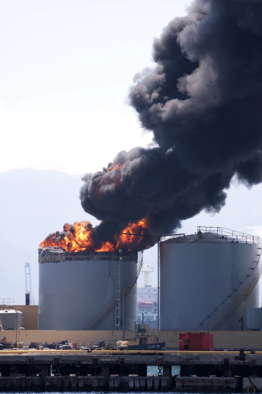 large industrial smoke and flames billow from two silos