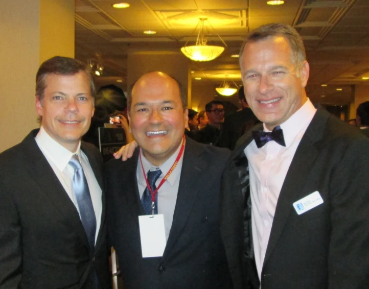 three men posing for the camera wearing ties and suits