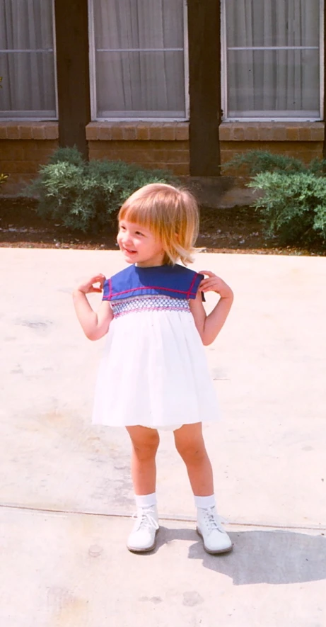 a little girl in a dress standing outside