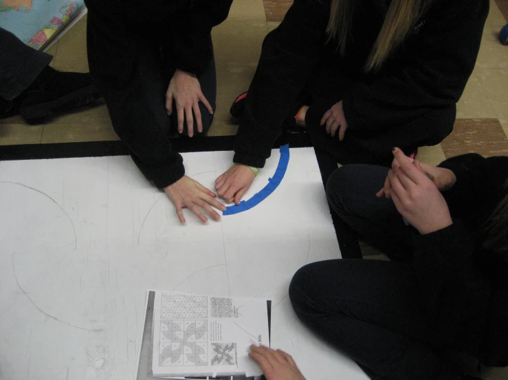 two people touching a white piece of paper with their hands