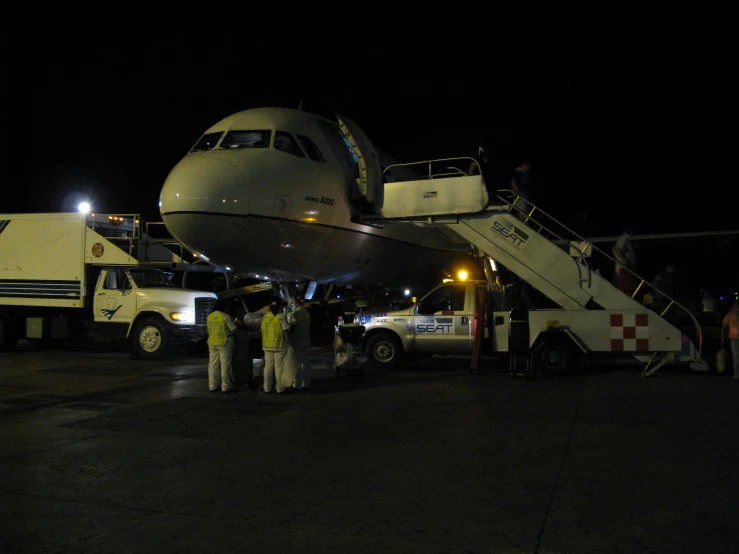 several people are standing near an airplane at night