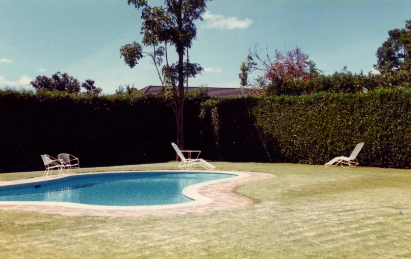 some lawn chairs are in front of the pool