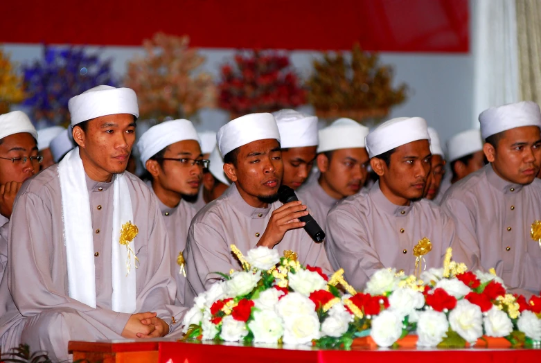 several men in white uniforms are holding a microphone