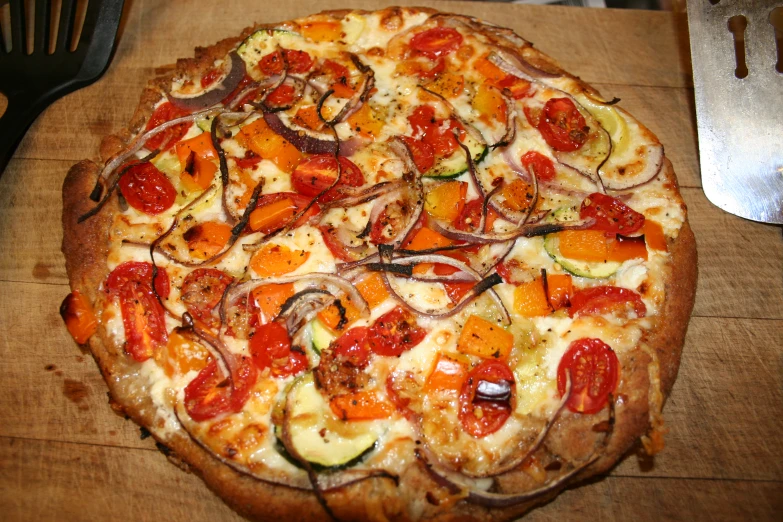 a pizza with cheese, tomatoes, zucchini and onions