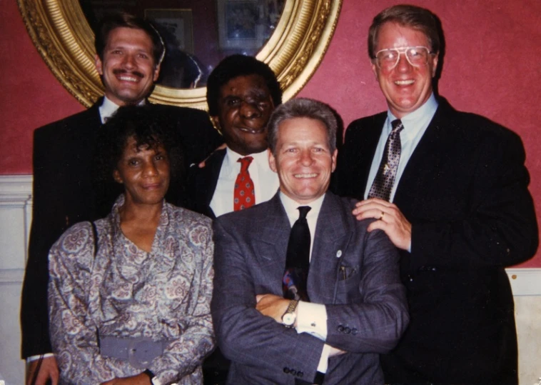 an older man posing with two men and a woman