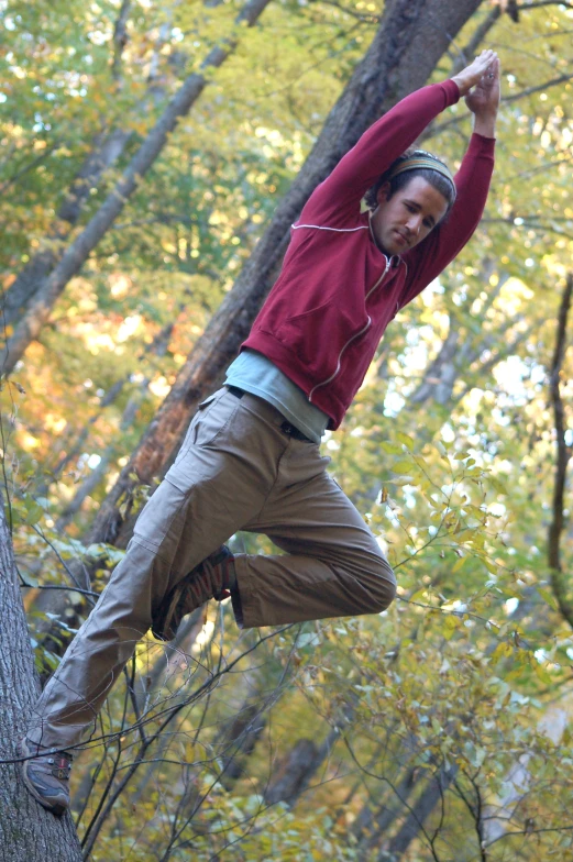 a young man stands on a tightrope high in the forest