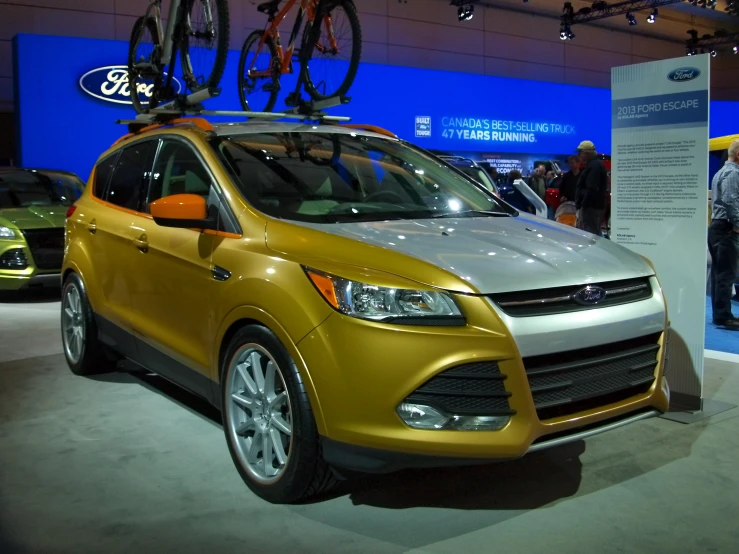 a gold car parked with a bike on the roof