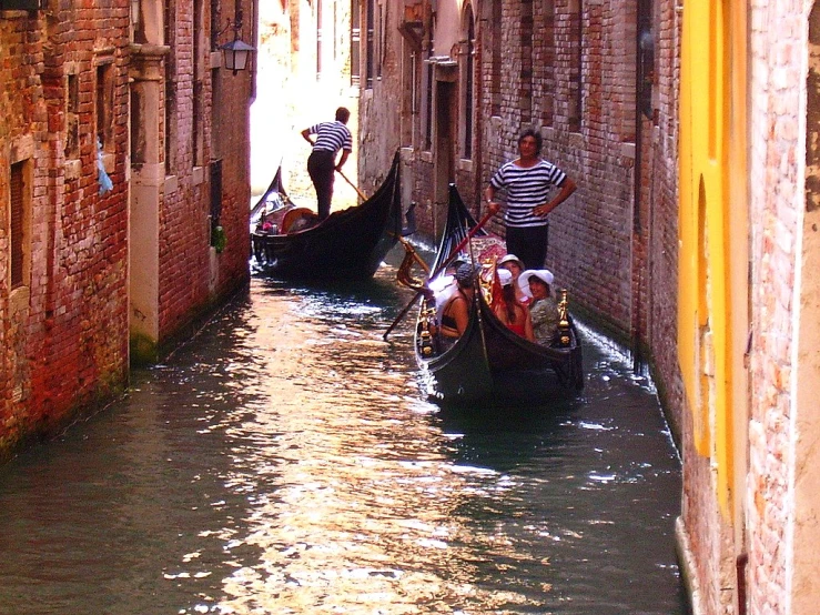 people riding down a narrow canal in the middle of the city