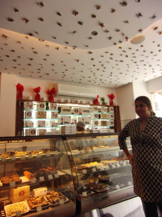 a baker standing next to a pastry display case