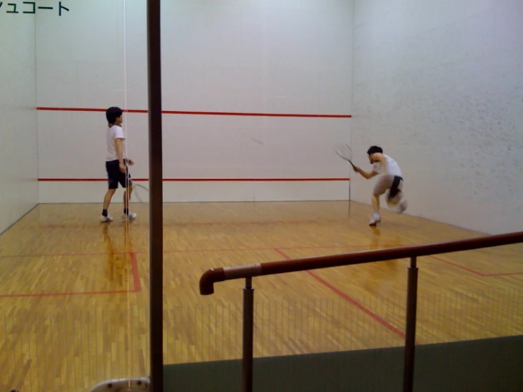 two guys playing badminton on a court indoors