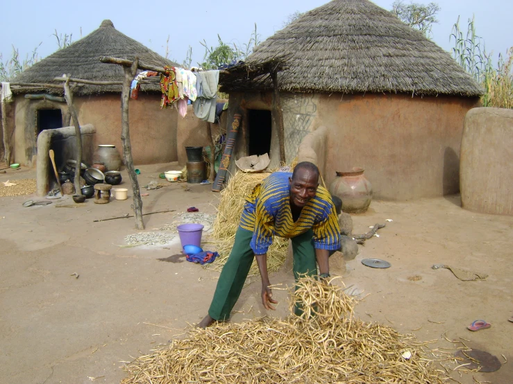 a woman sits near several thatched huts in africa