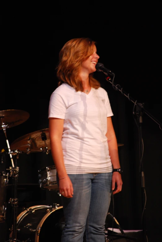 the girl stands in front of a microphone as she sings