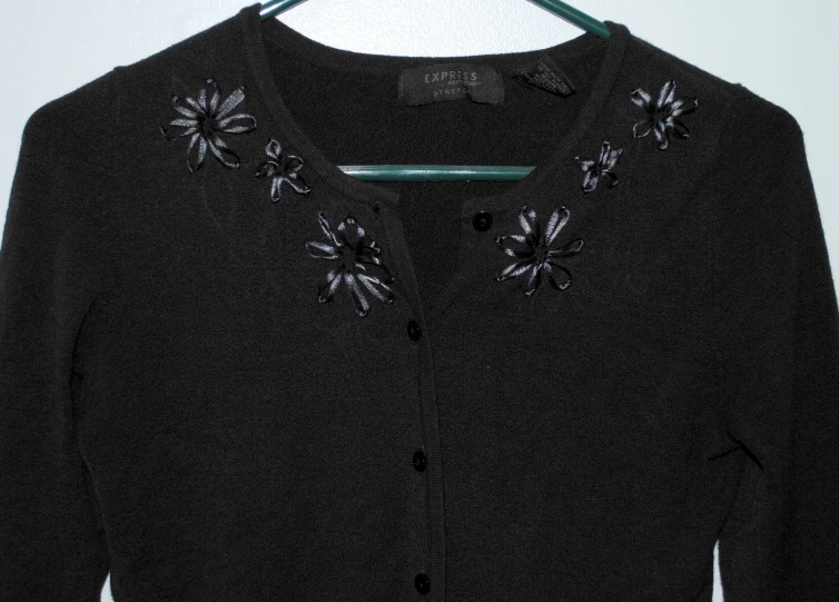 a black sweater with an embroidered flower on it