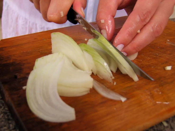 someone chopping onion on a wooden  board with scissors