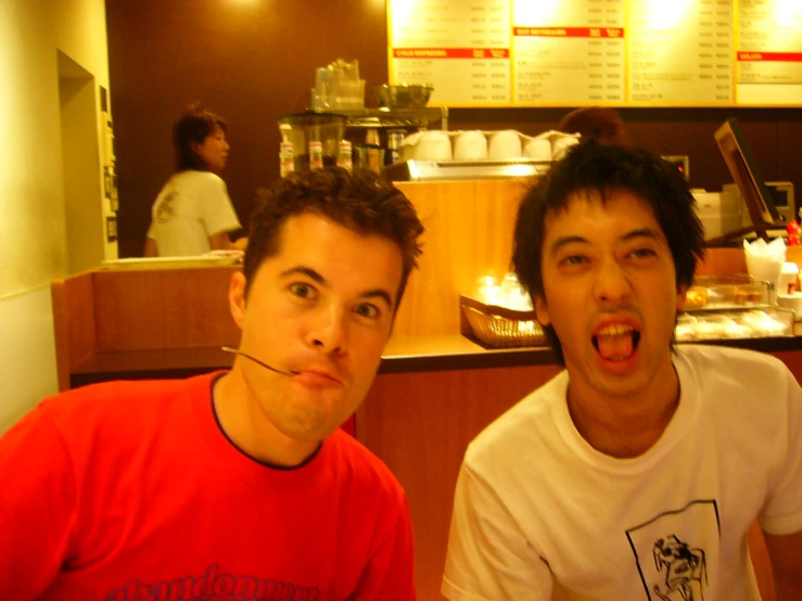 two young men sitting side by side at a restaurant