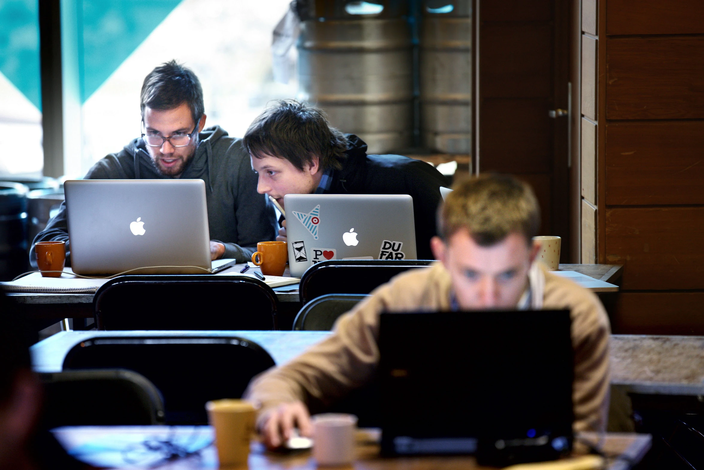 two men work on computers at some tables