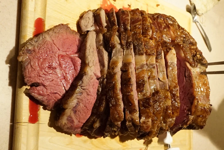a roast meat is on a  board and sliced up