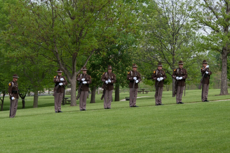 a bunch of men in uniforms stand in front of some trees