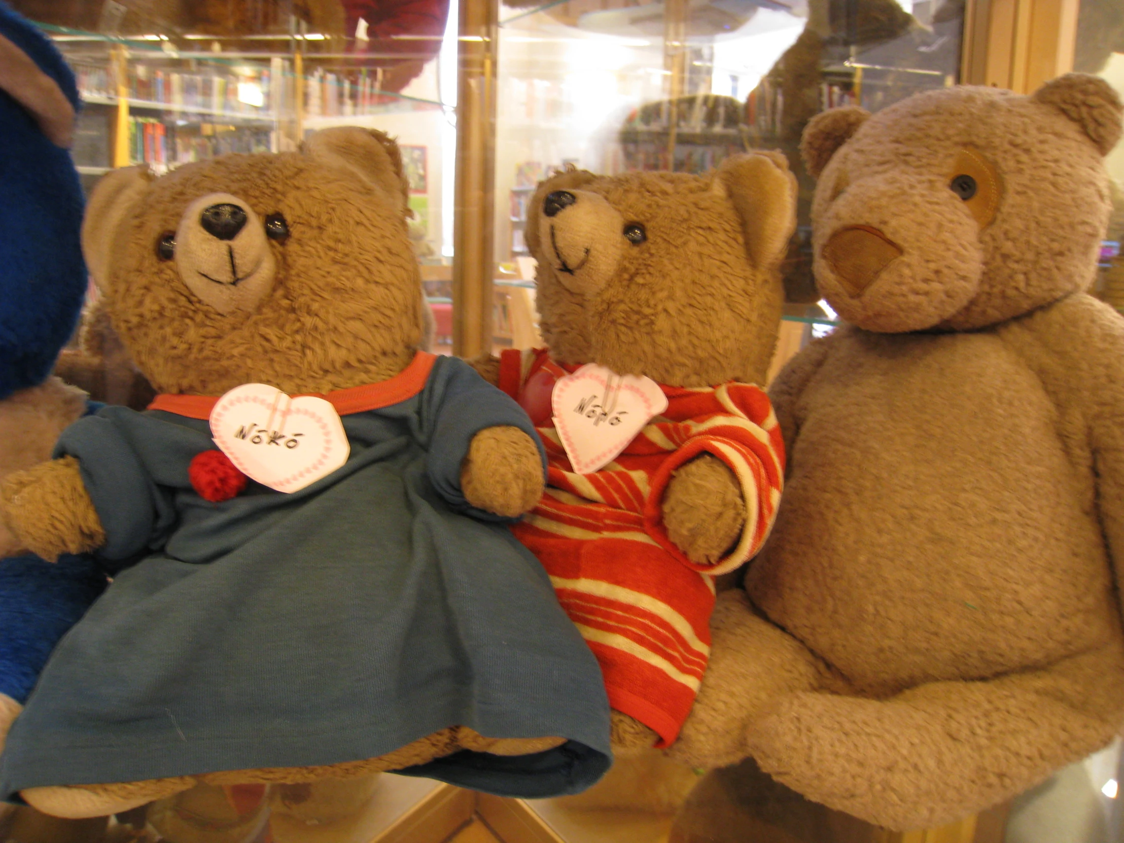 three stuffed teddy bears sitting in front of a window