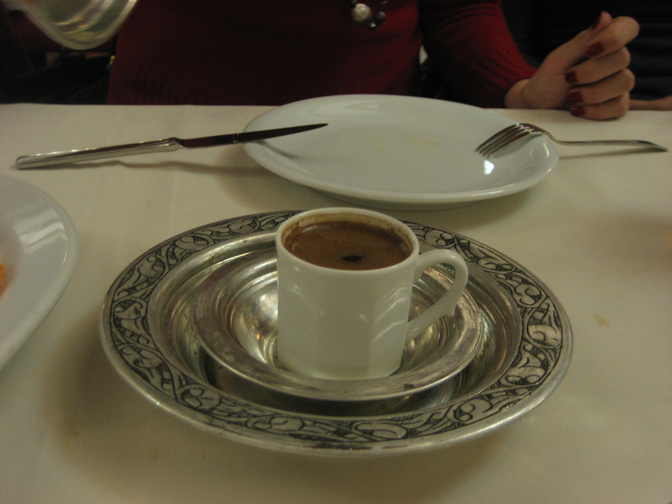 a cup of coffee on top of a silver plate