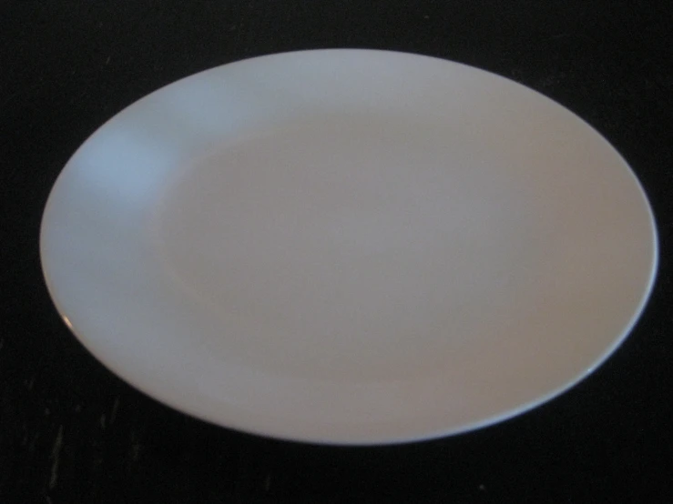 a white plate sits empty on a black table