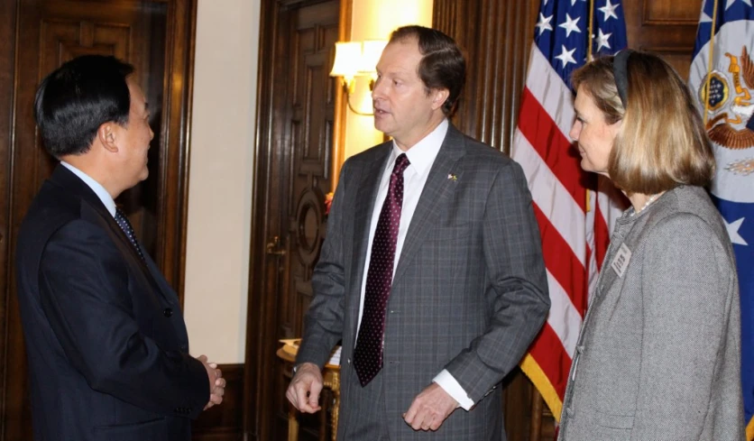 a man standing between two women in suit and ties