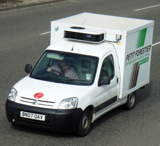 a white delivery truck on the road with another white vehicle nearby