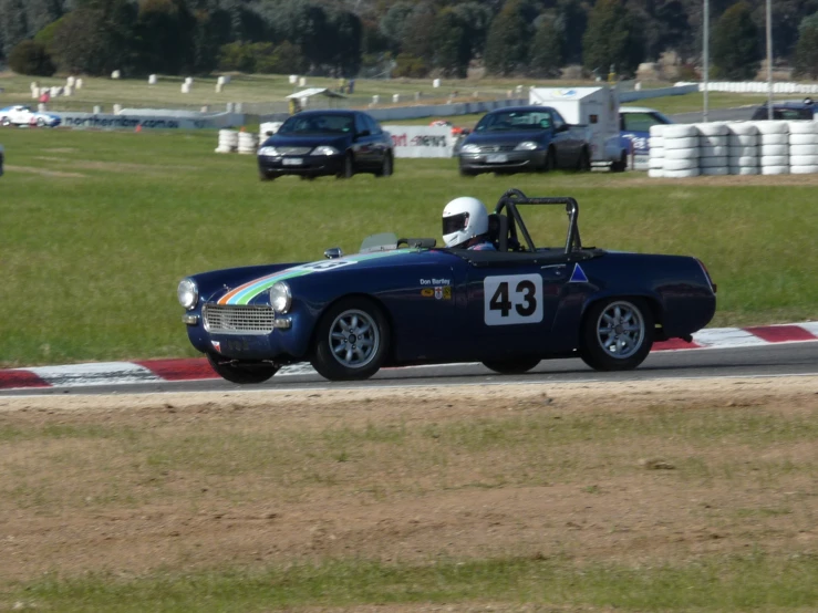 an old blue race car is racing on the road