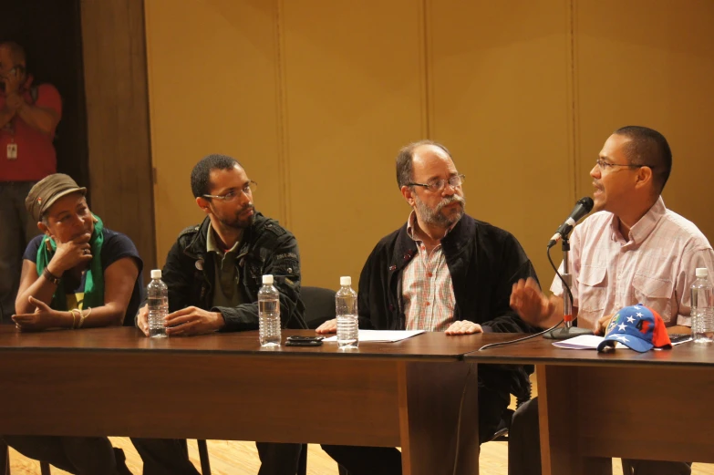 three men are sitting at a table talking