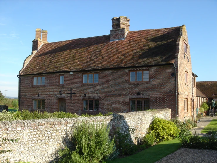 a brick house with a stone wall and tall chimneys