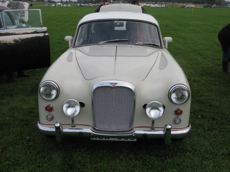 an old fashion car parked on grass next to other cars